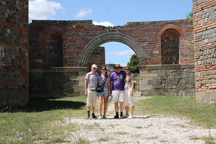 Four people are posing in front of the Felix Romuliana complex. in East Serbia.