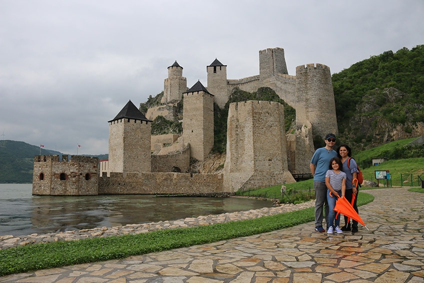 Family is standing in front of the Golubac fortress.